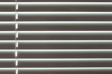 Closed modern white window blinds as background, closeup view