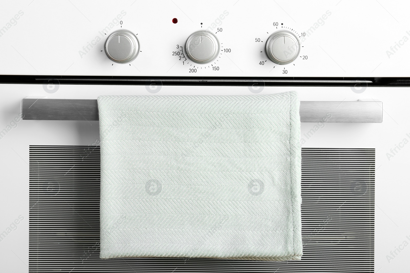 Photo of Modern electric oven with towel, closeup view