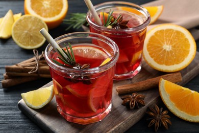 Photo of Aromatic punch drink and ingredients on black wooden table