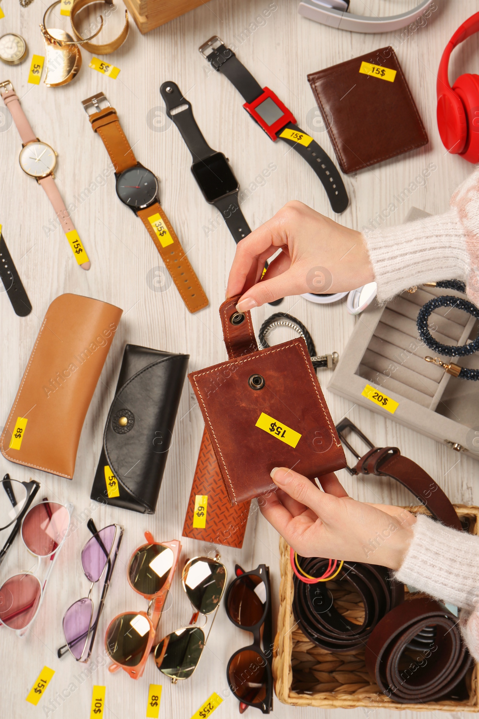 Photo of Woman holding wallet near table with different stuff, top view. Garage sale