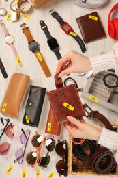 Photo of Woman holding wallet near table with different stuff, top view. Garage sale