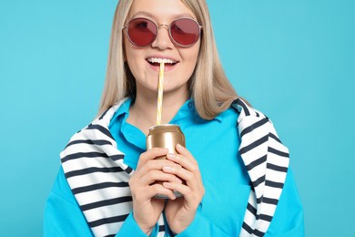 Photo of Beautiful happy woman drinking from beverage can on light blue background