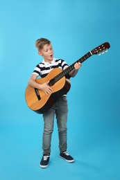 Photo of Little boy playing guitar on color background