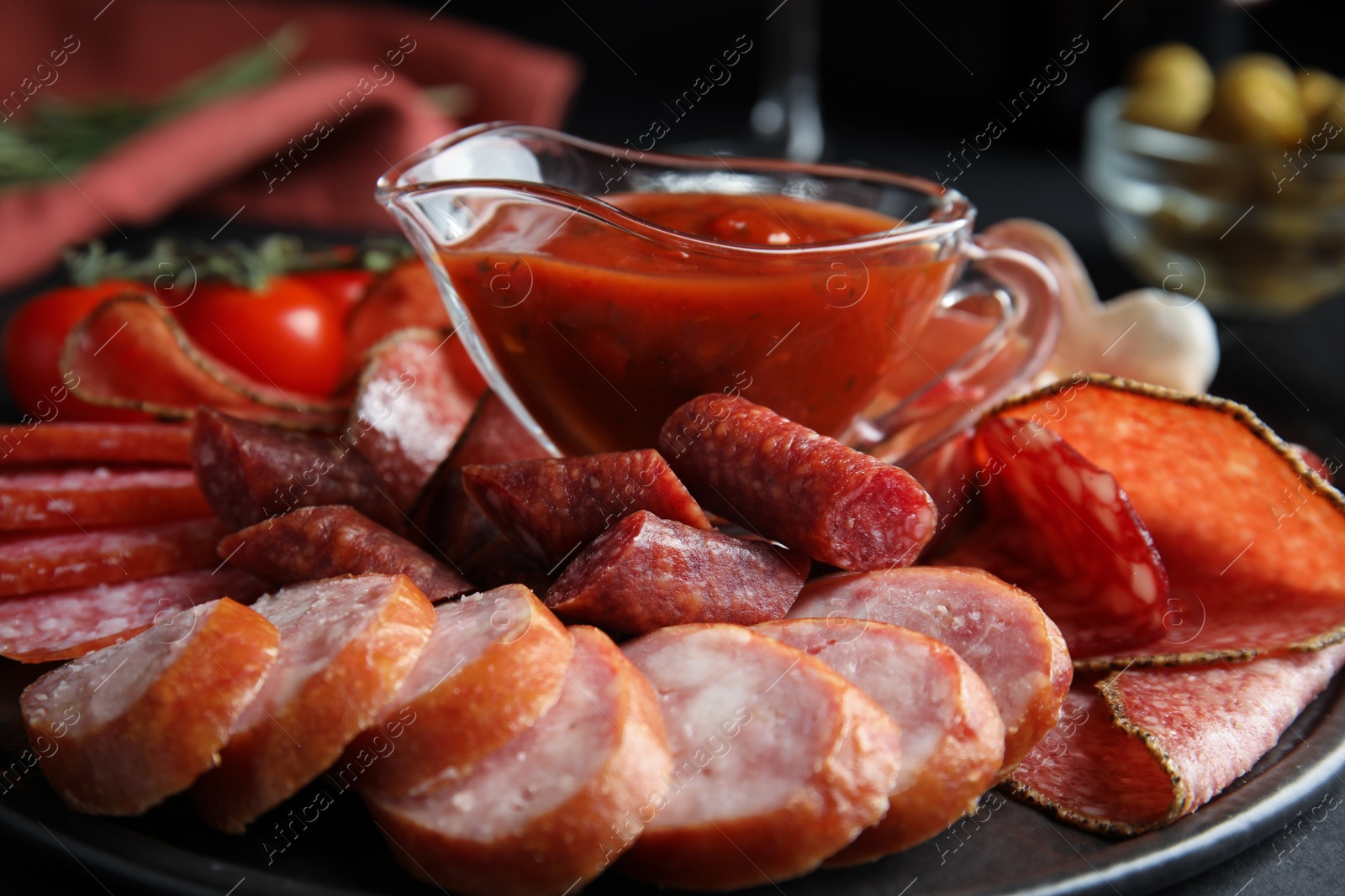 Photo of Different types of sausages with sauce served on black table, closeup