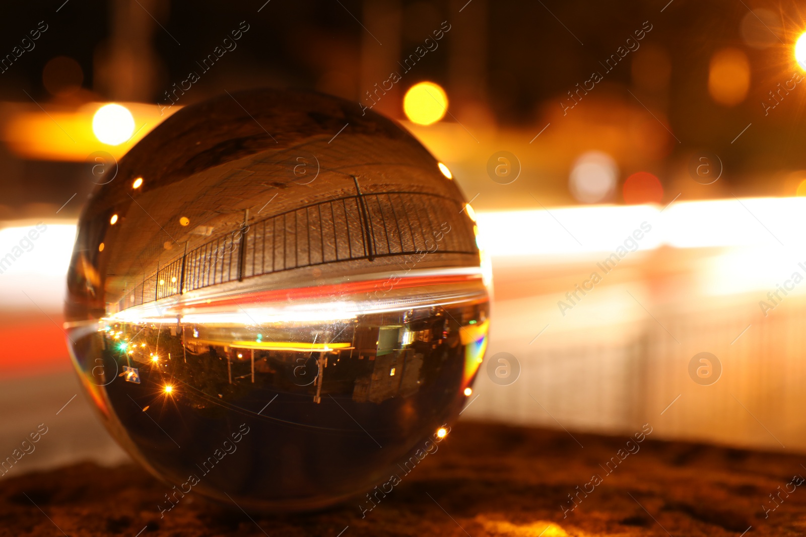 Photo of Beautiful city street, overturned reflection. Crystal ball at night, closeup. Space for text