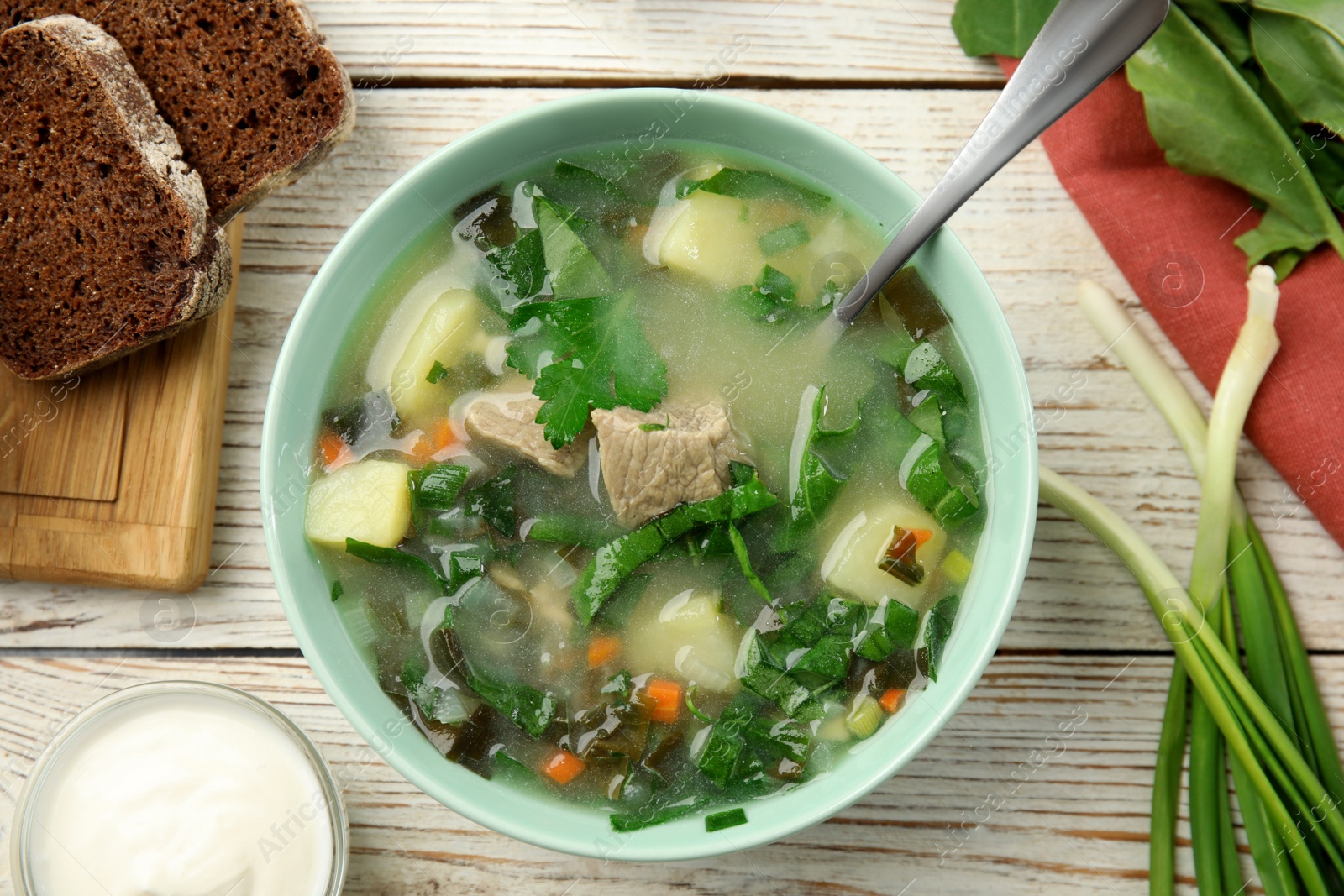 Photo of Delicious sorrel soup with meat served on wooden table, flat lay