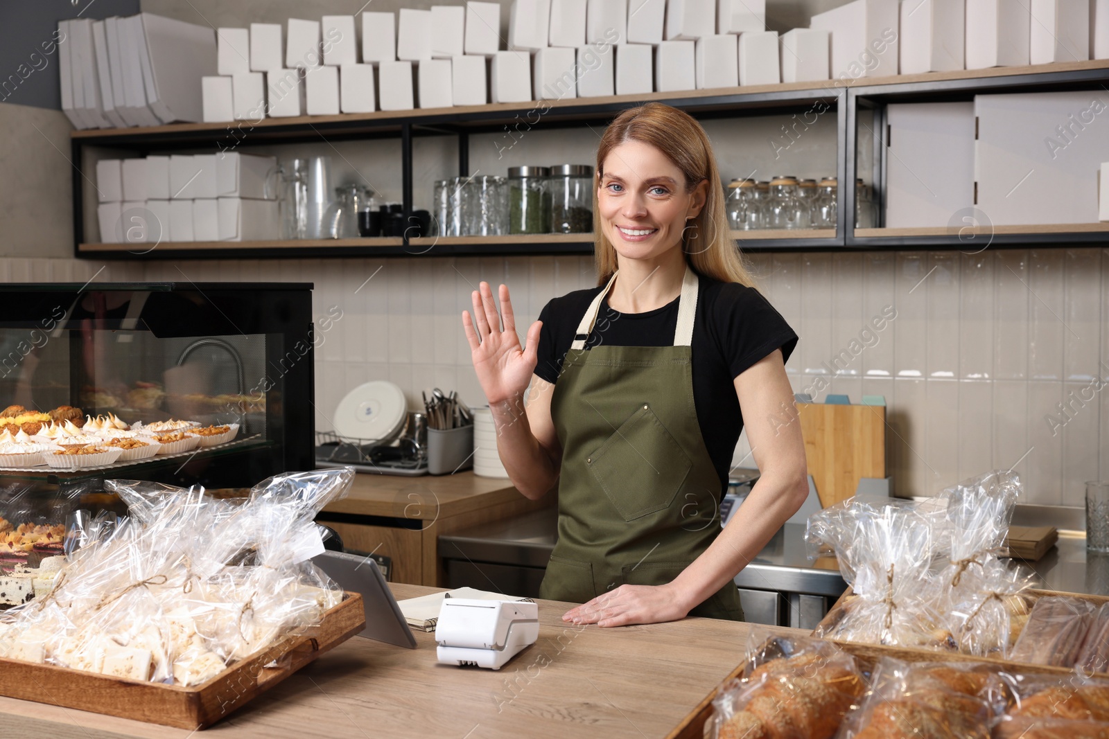 Photo of Happy seller at cashier desk in bakery shop