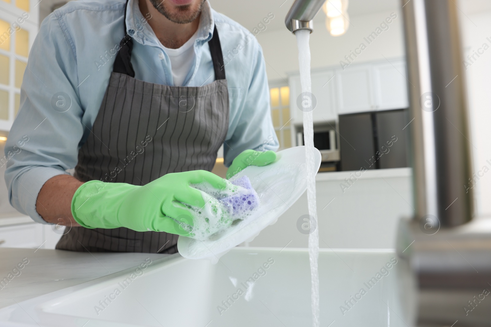 Photo of Man washing plate above sink in kitchen, closeup