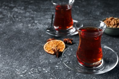 Photo of Glasses of traditional Turkish tea and ingredients on grey textured table, closeup. Space for text