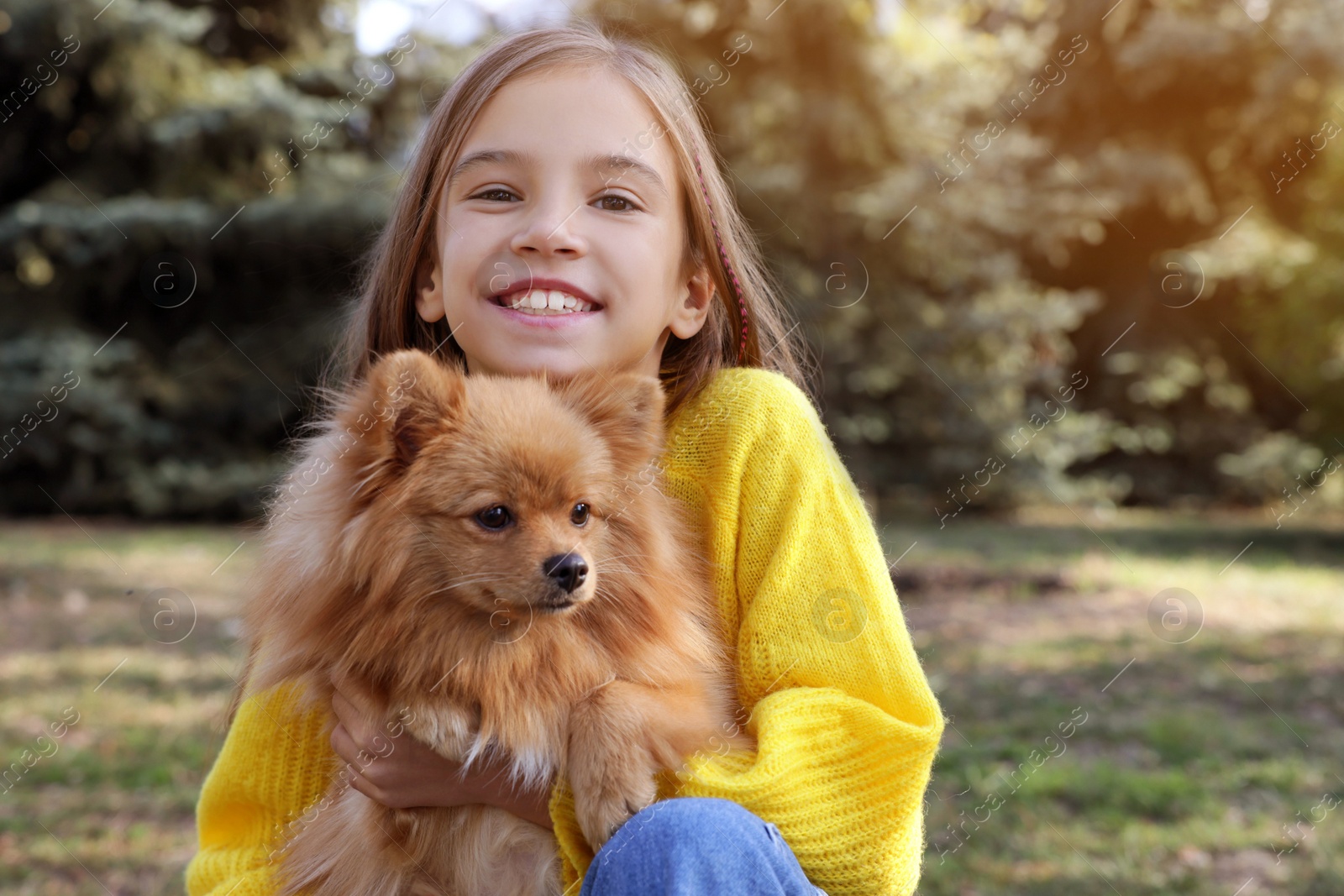 Photo of Little girl with her cute dog in park. Autumn walk