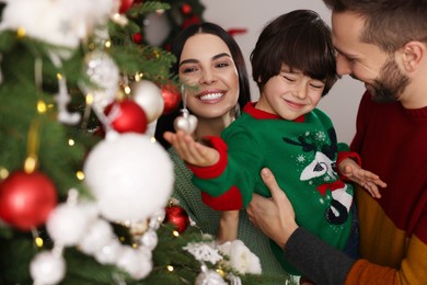 Happy family decorating Christmas tree together at home