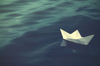 Image of White paper boat floating on river. Retro photo effect
