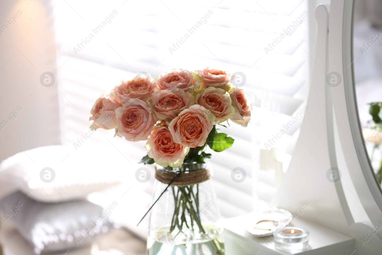 Photo of Glass vase with beautiful flowers on dressing table in modern room interior