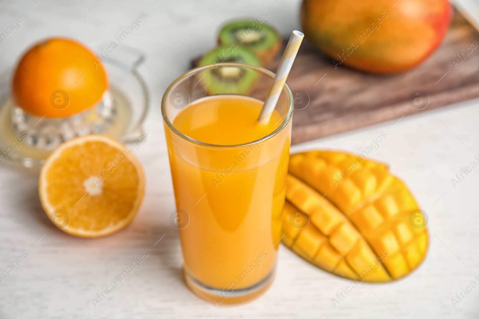 Photo of Glass of fresh mango drink and tropical fruits on wooden table