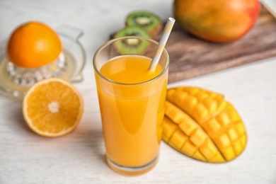 Glass of fresh mango drink and tropical fruits on wooden table