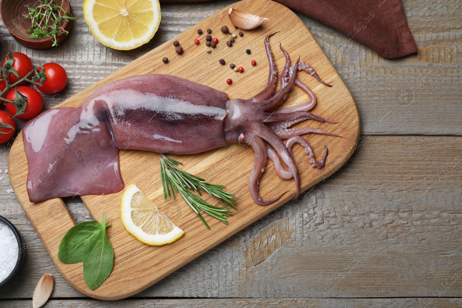 Photo of Flat lay composition with fresh raw squid and garnish ingredients on wooden table