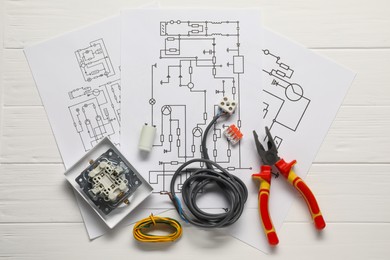 Wiring diagrams, wires, pliers and disassembled light switch on white wooden table, top view