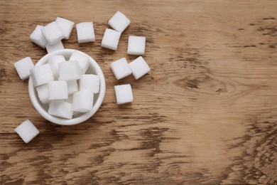 Photo of White sugar cubes on wooden table, flat lay. Space for text