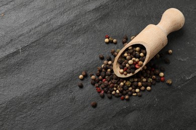 Photo of Aromatic spice. Different peppers in scoop on black table, top view. Space for text