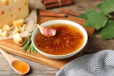 Photo of Delicious fig jam with fresh fruit on wooden table, closeup