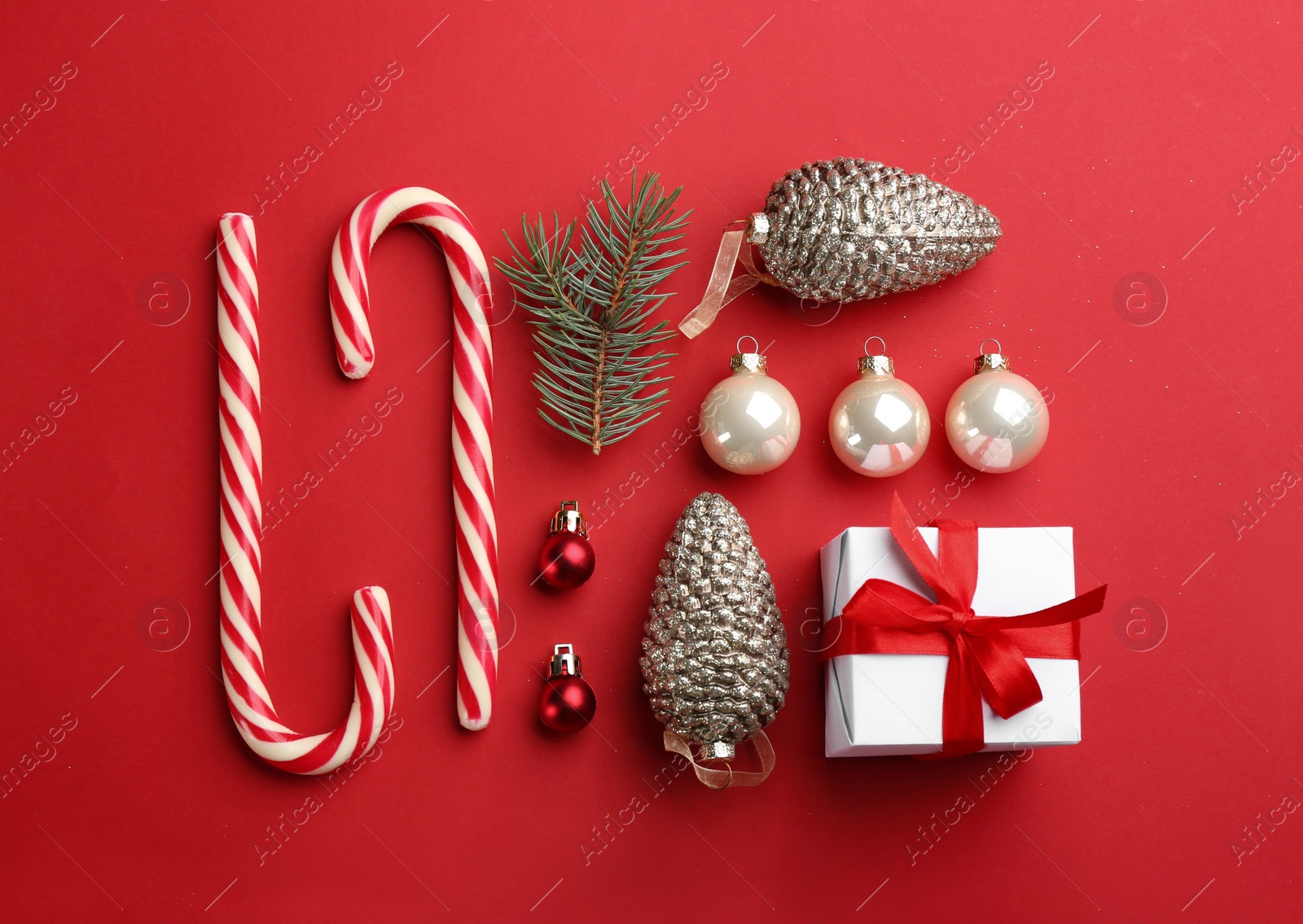 Photo of Flat lay composition with candy canes and Christmas decor on red background