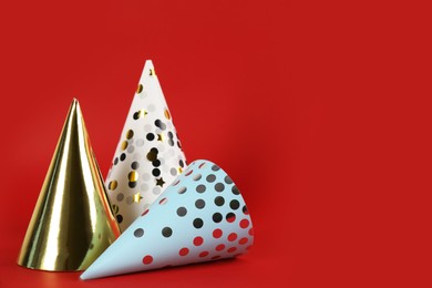 Bright party hats on red background. Space for text