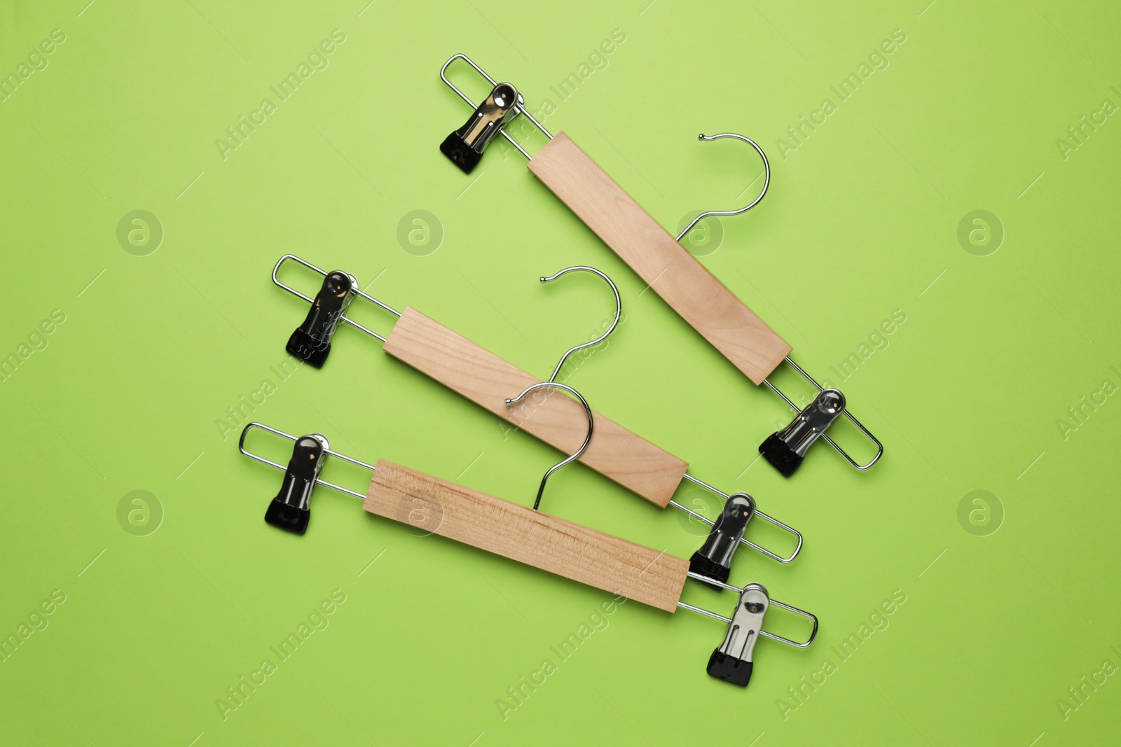 Photo of Empty clothes hangers on green background, flat lay