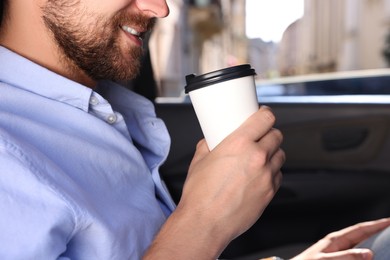 Coffee to go. Man with paper cup of drink in car, closeup