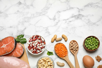 Photo of Products rich in protein on white marble table, flat lay. Space for text