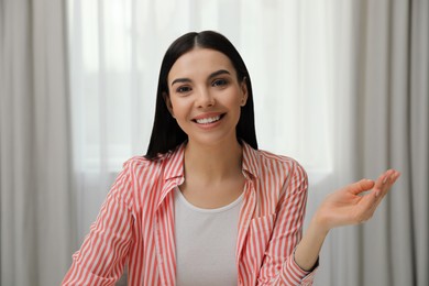 Beautiful young woman conducting webinar in room, camera view