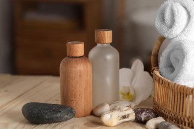 Photo of Composition with spa products and plumeria flower on wooden table in bathroom, closeup