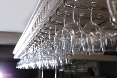 Photo of Set of empty clean glasses on bar racks