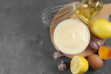 Photo of Fresh mayonnaise sauce in bowl and ingredients on grey table, flat lay. Space for text