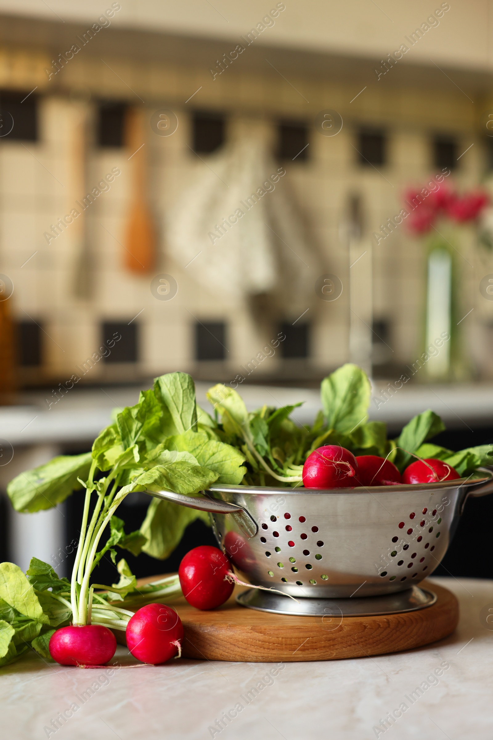 Photo of Metal colander with fresh radishes on white table