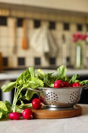 Photo of Metal colander with fresh radishes on white table