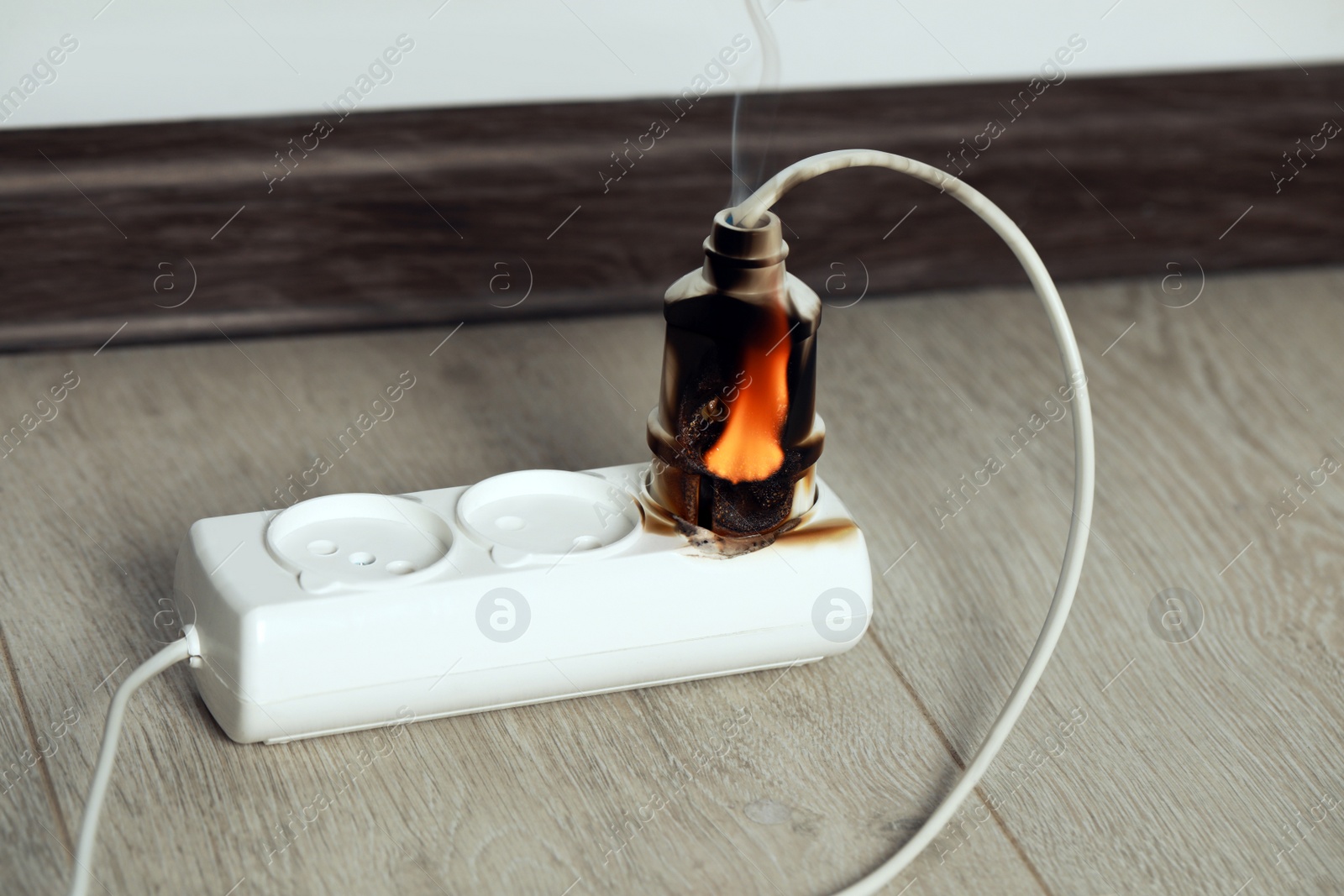 Photo of Inflamed plug in power strip indoors. Electrical short circuit