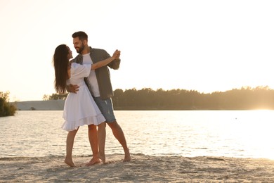 Photo of Happy couple dancing near river on sunny day. Space for text