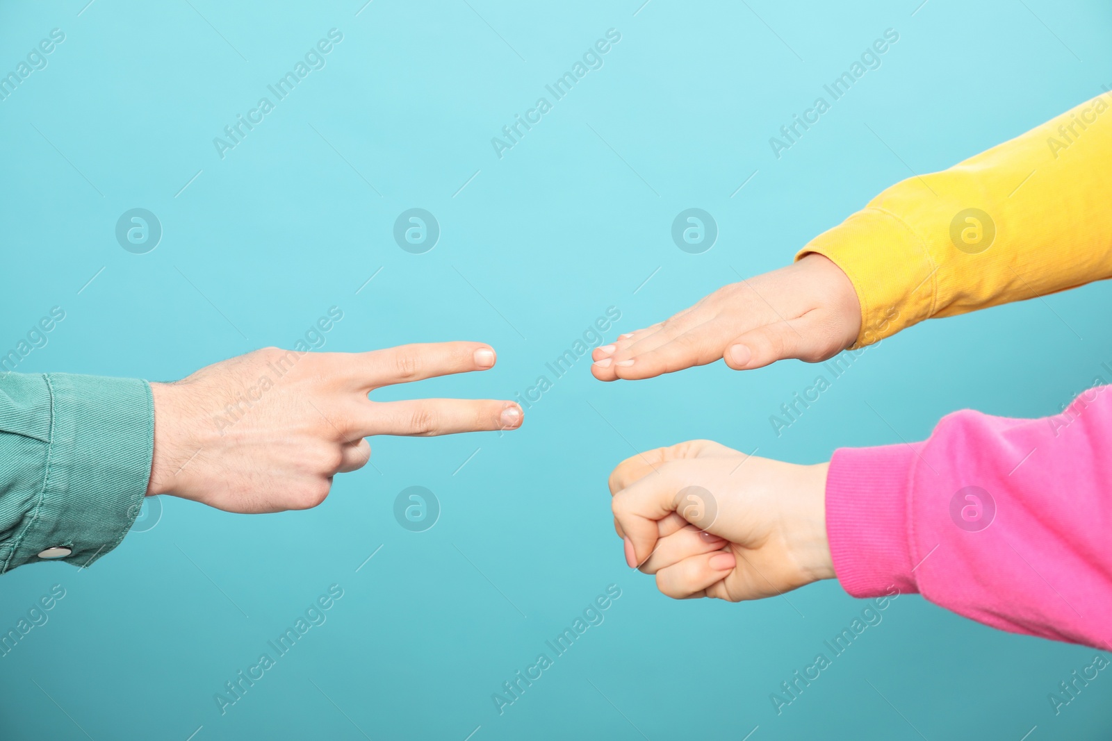 Photo of People playing rock, paper and scissors on light blue background, closeup