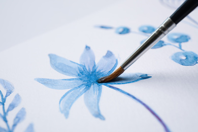 Photo of Painting flower with blue watercolor on white paper, closeup
