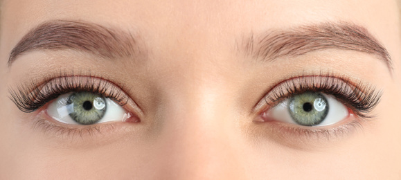 Young woman with beautiful eyelashes after extension procedure, closeup. Banner design