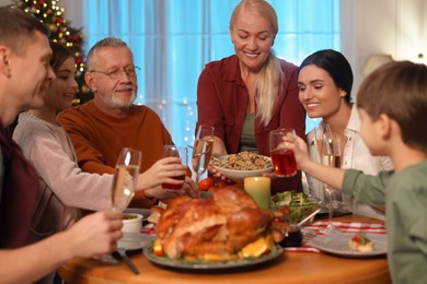 Photo of Woman with bowl of traditional Christmas Slavic dish kutia and her family during festive dinner at home