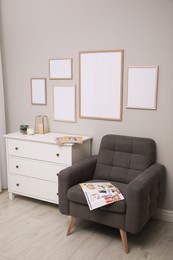 Empty frames hanging on grey wall over white chest of drawers in room. Mockup for design