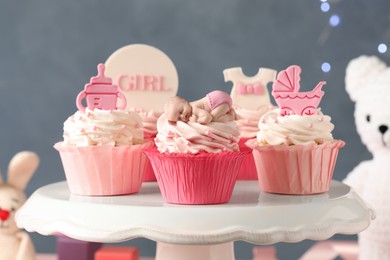 Photo of Beautifully decorated baby shower cupcakes for girl with cream and toppers on stand