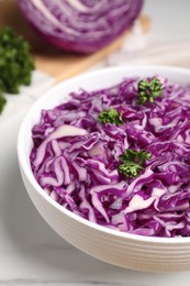 Photo of Bowl with shredded red cabbage and parsley on white table, closeup
