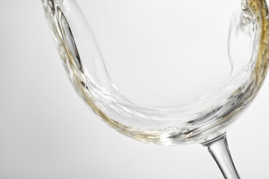 Pouring white wine into glass on light background, closeup