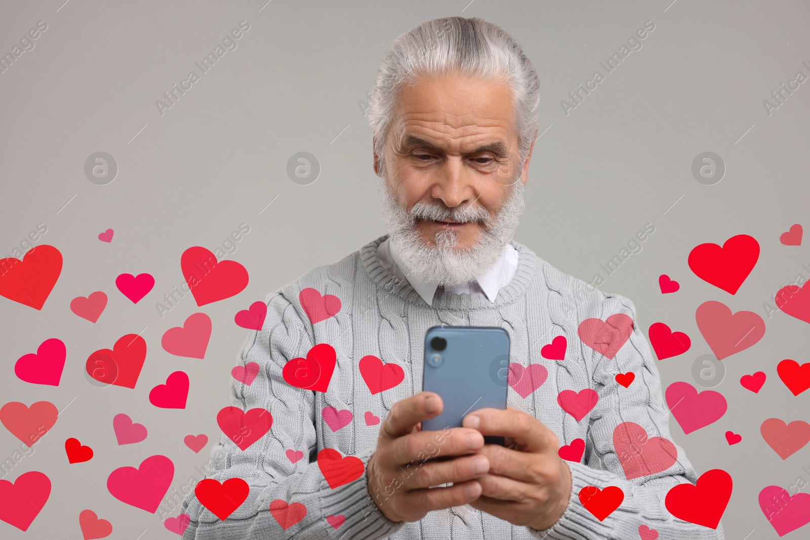 Image of Long distance love. Man chatting with sweetheart via smartphone on grey background. Hearts flying out of device and swirling around him