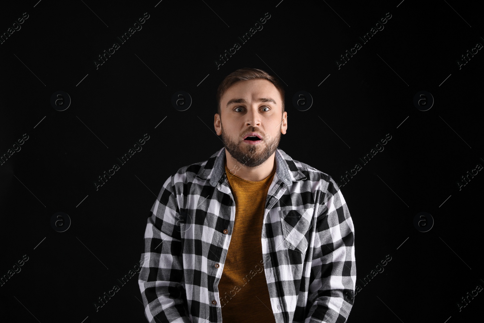 Photo of Portrait of emotional young man on black background. Personality concept