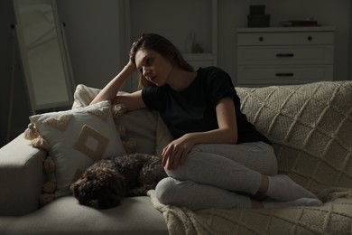 Photo of Sad young woman and her dog on sofa at home