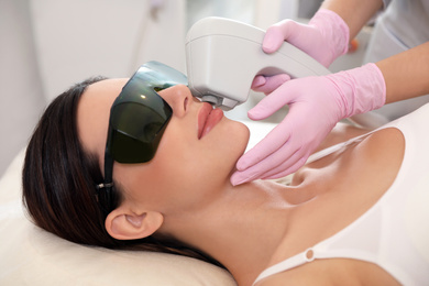 Photo of Young woman undergoing laser epilation procedure in beauty salon