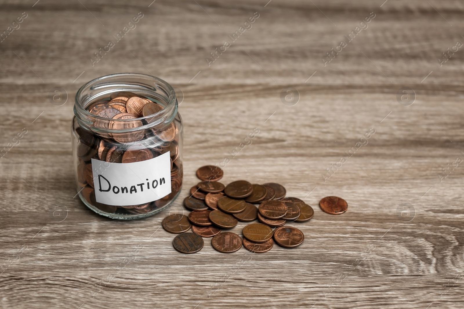 Photo of Donation jar and coins on wooden table. Space for text